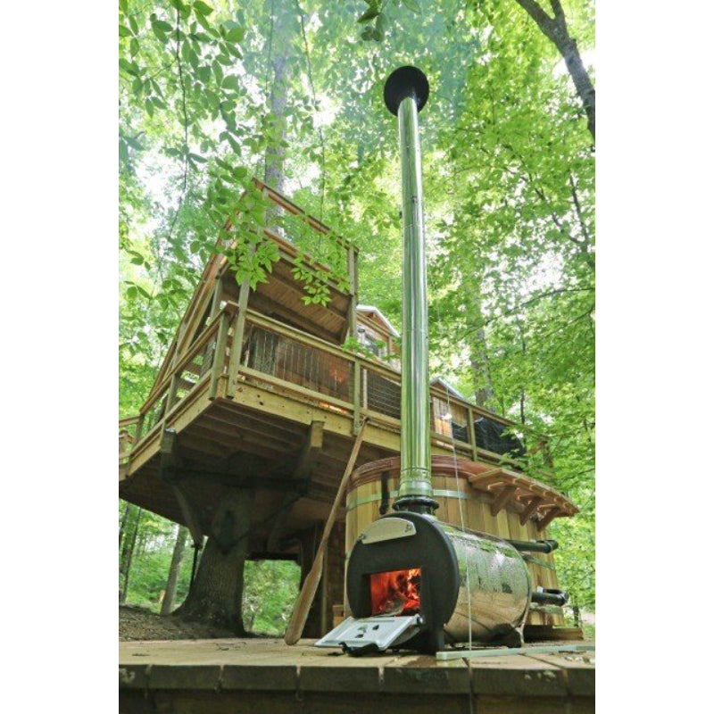 Woodfired Ofuro Tub with wood stove in foreground beside a tree house in the forest.
